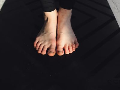 Close up of feet grounding on a black yoga mat
